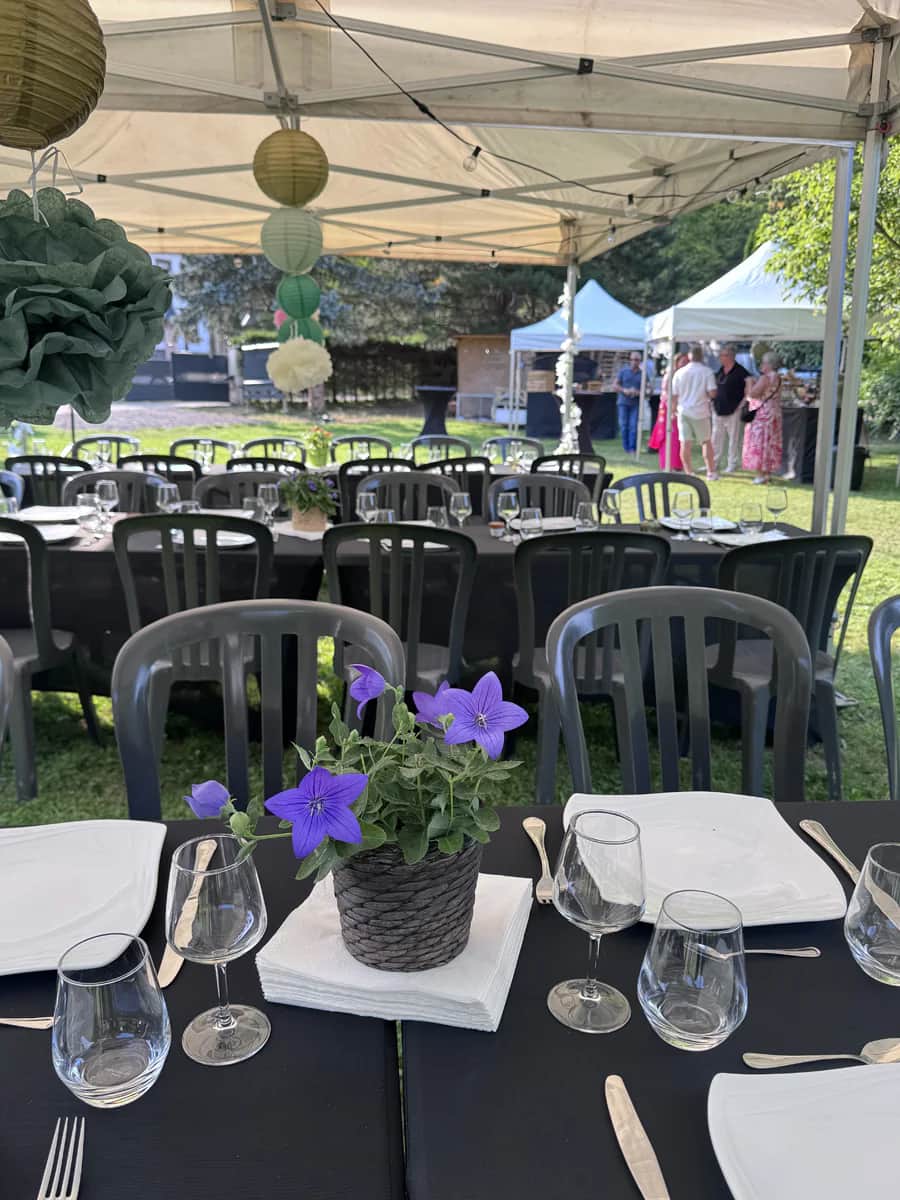 Tables, chaises et vaisselle dressées sous un barnum