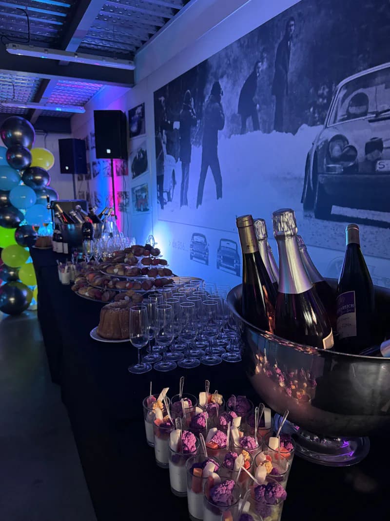 Verrines, verres et bouteilles disposés sur un buffet de réception éclairé en bleu
