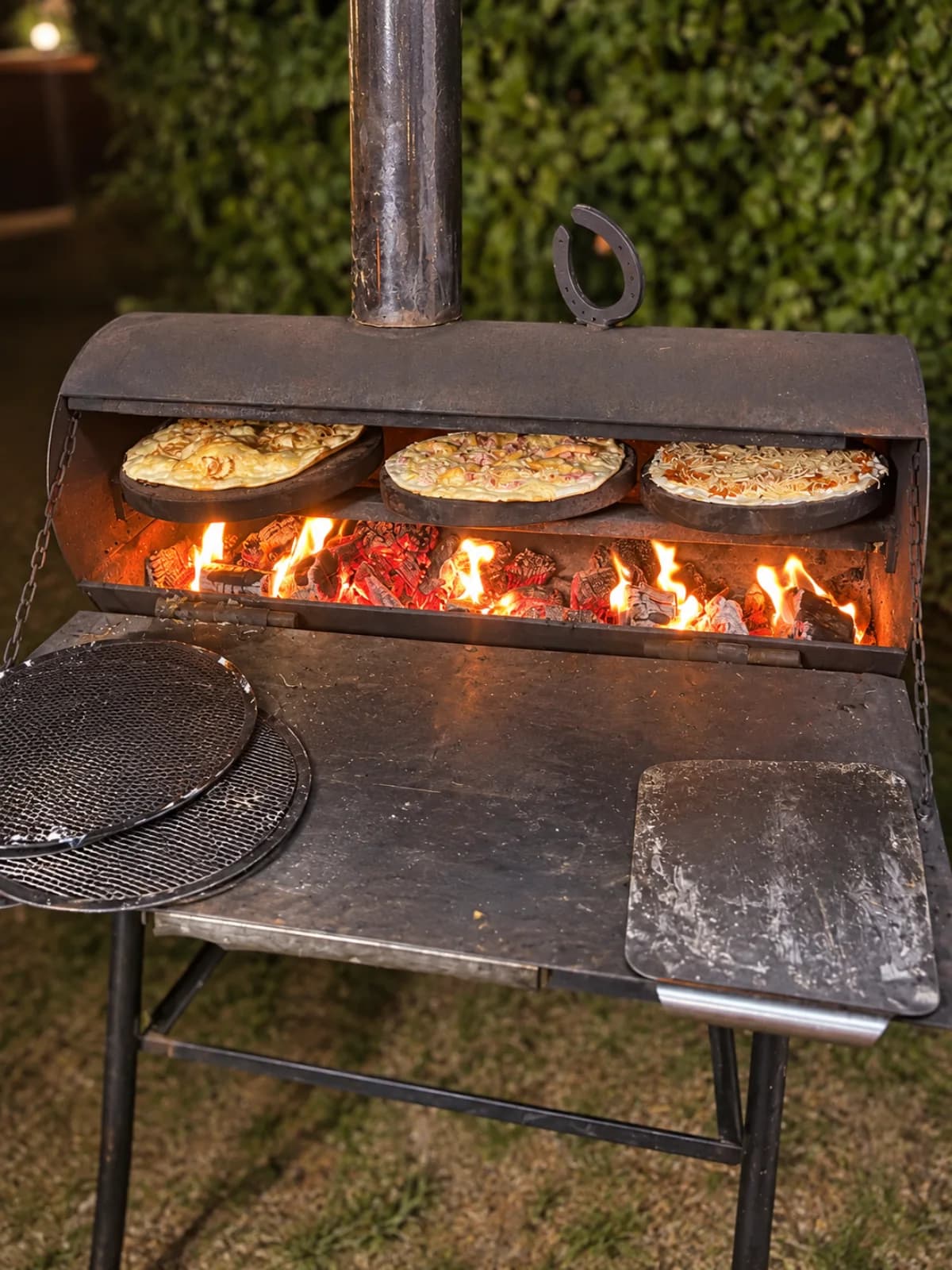 Plusieurs tartes flambées cuisent au-dessus des braises du four à bois